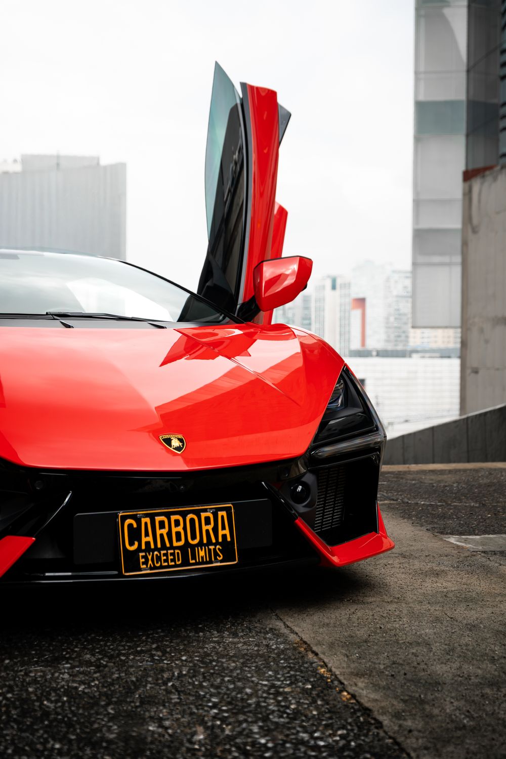 Lamborghini Revuelto rojo con la puerta de tijera levantada, en el taller de Carbora