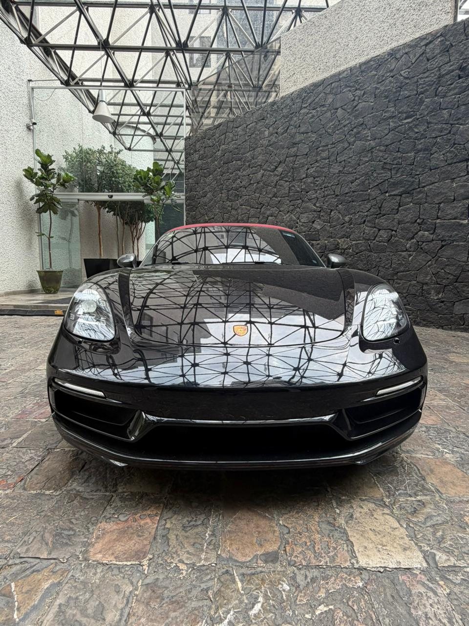 El Boxster negro antes de la transformación, con toldo rojo.