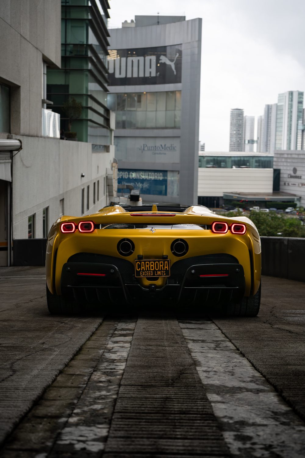 Vista trasera de un Ferrari SF90 con placa promocional CARBORA.