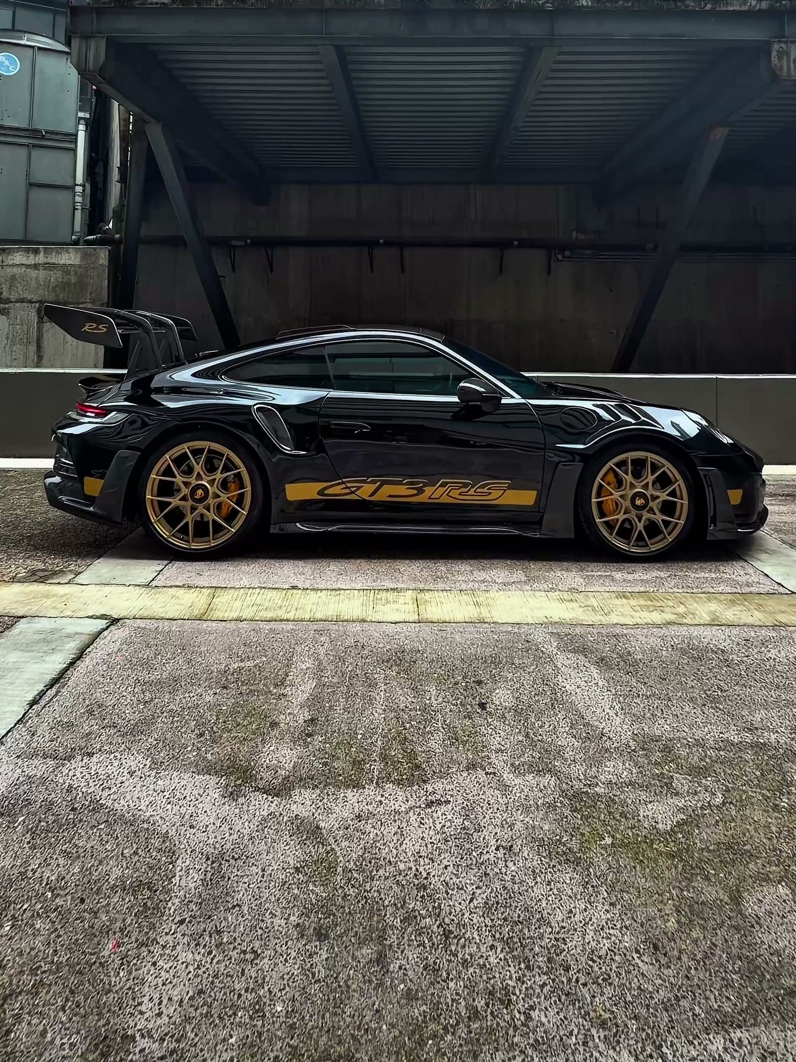 Perfil completo del Porsche 911 en configuración tipo GT3 RS: se aprecian el ensanchamiento de la carrocería, los rines dorados de configuración tipo center-lock y el alerón con soportes de cisne.